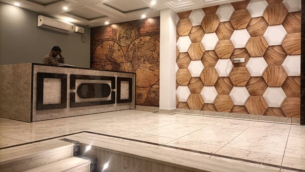 A reception area with a marble floor, a wooden wall with hexagonal patterns, and a large world map mural. - Hotel The Tark (New Delhi)