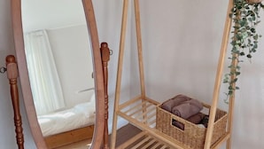 A room with a bed, a mirror, a hanging plant, and a wicker basket. - GLA Aewol (Jeju City)