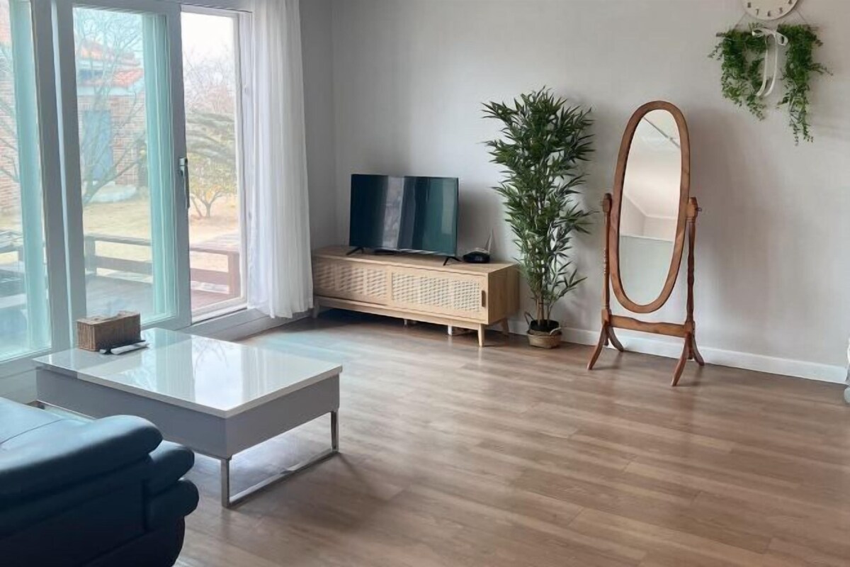 Un salón moderno con televisor, espejo, planta y mueble de madera.
