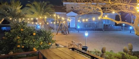 An outdoor area with a wooden bench, a swing set, and string lights.