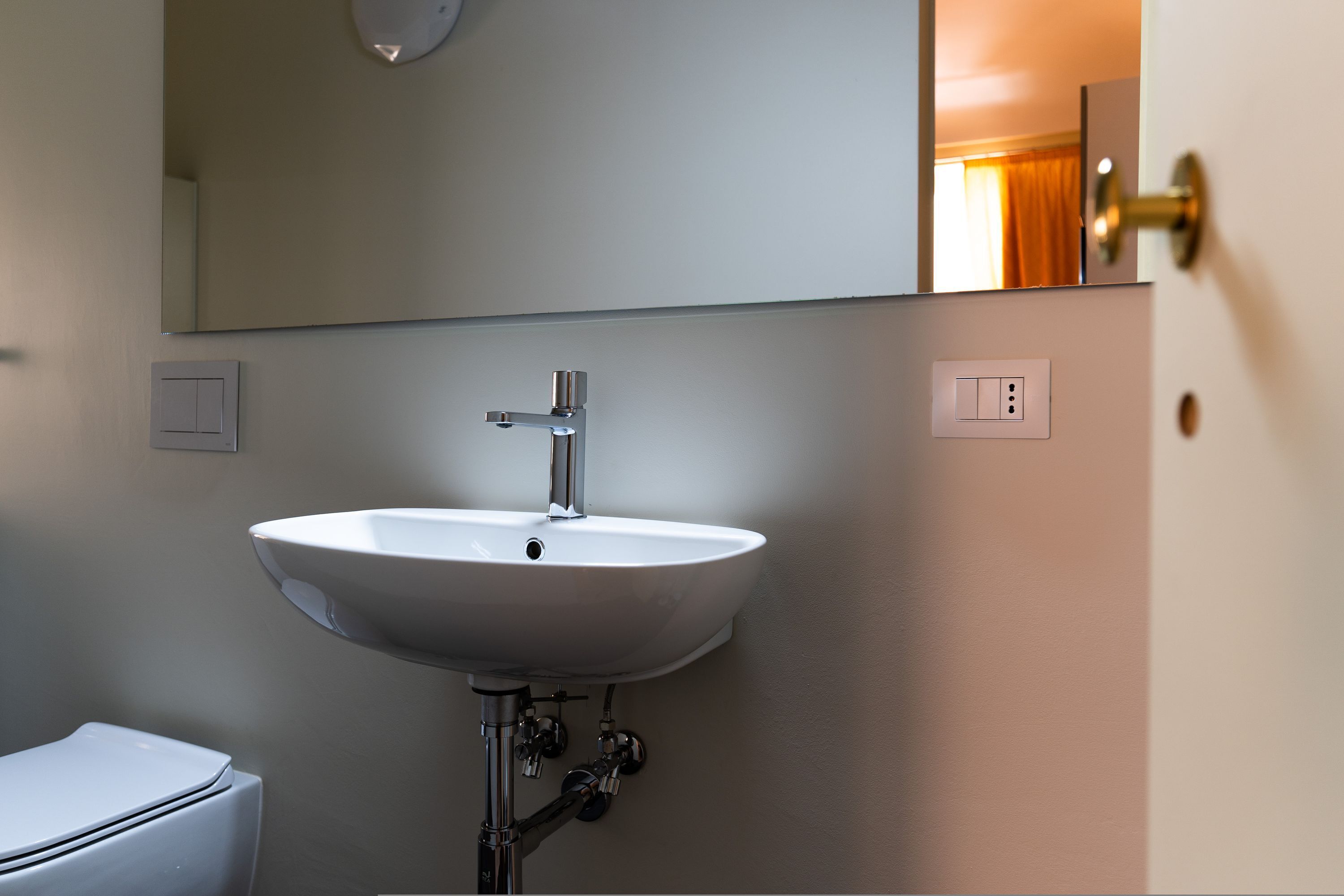 A bathroom with a white sink, a mirror above it, and a toilet.