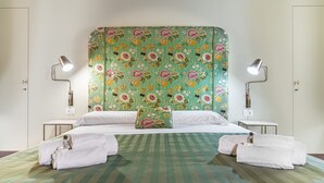 A hotel room with a bed, two bedside tables, and a floral headboard. - Capo10 Liberty C1 in Syracuse (Syracuse)