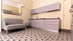A modern bathroom with a grey sofa, a sink, and patterned floor tiles. - Capo10 Liberty C1 in Syracuse (Syracuse)