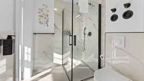 A modern bathroom with a glass shower enclosure, a toilet, and a sink.