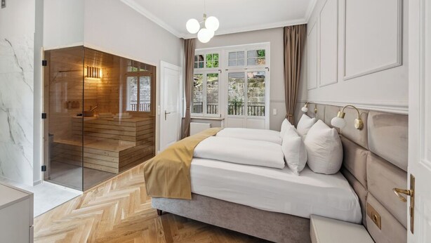 Een moderne slaapkamer met een groot bed, een douche met glazen wanden en uitzicht op de omgeving.