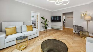 Una sala de estar moderna con un sofá, un televisor, una planta y una lámpara.