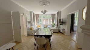 Ein großzügiger Essbereich mit einem großen Tisch und Stühlen, einer Couch und einem an der Wand montierten Fernseher.