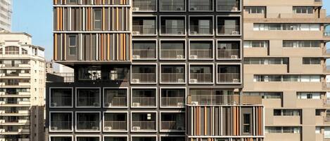 A modern high-rise building with multiple balconies, large windows, and a mix of residential and commercial spaces.