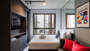 Ein modernes Hotelzimmer mit Bett, einer Couch, einem Fernseher und einem großen Fenster.