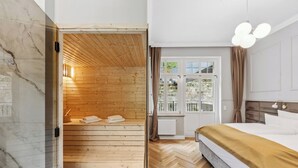 Habitación de hotel moderna con sauna de madera, una cama grande y vistas al exterior.