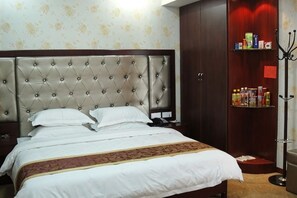 A hotel room with a large bed, a wardrobe, and a shelf with toiletries.