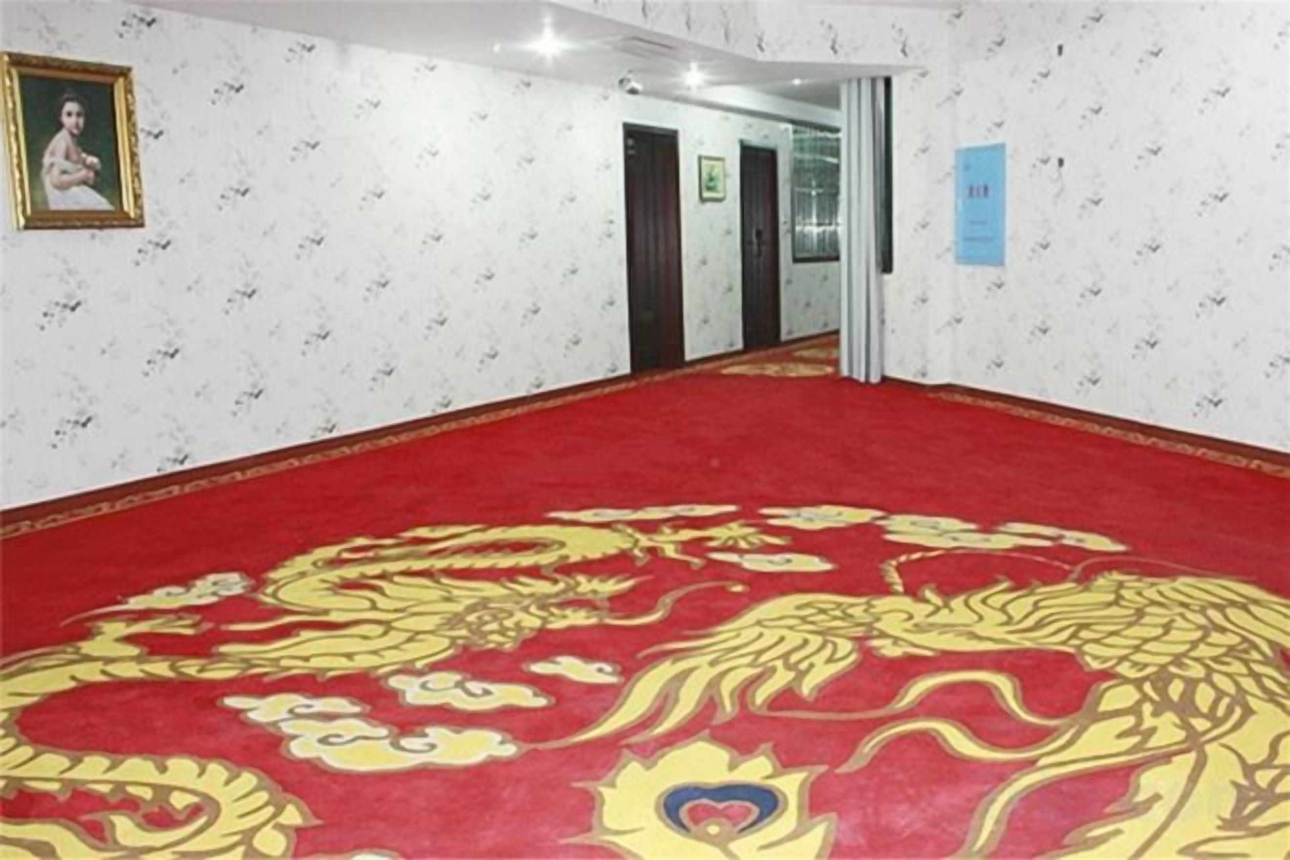 Een hotelgang met een rood tapijt en behang met een patroon.