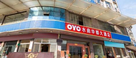 A hotel with a prominent OYO branding, a large entrance, and a sign indicating it is a hotel.