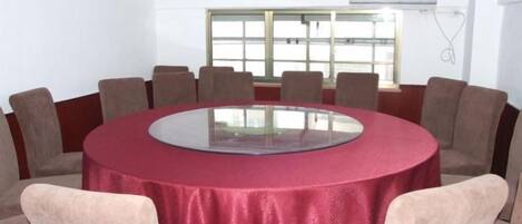 A conference room with a round table, beige chairs, and a red tablecloth.