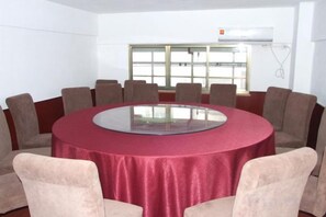 Een vergaderzaal met een ronde tafel, beige stoelen en een rode tafelkleed.