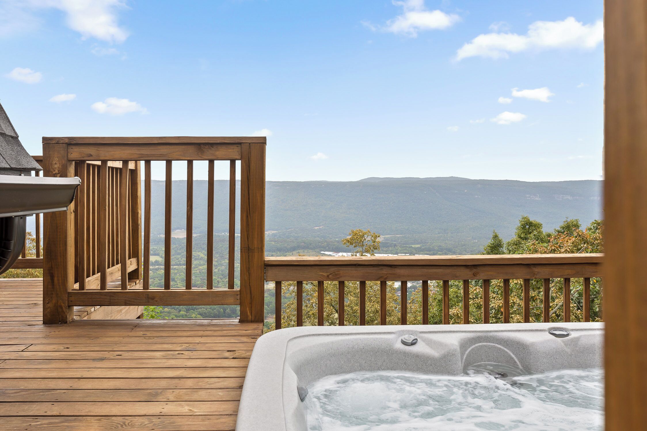 Une terrasse en bois avec un jacuzzi et une vue sur les montagnes.