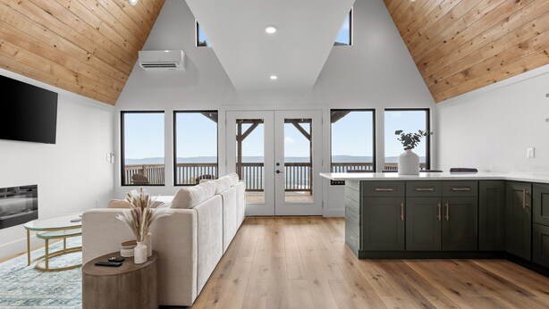 A modern interior with a wooden ceiling, a sofa, a dining area, and large windows. - Mountain’s Edge by Appalachian A-Frames, Mountain View, Hot Tub, WiFi (Trenton)