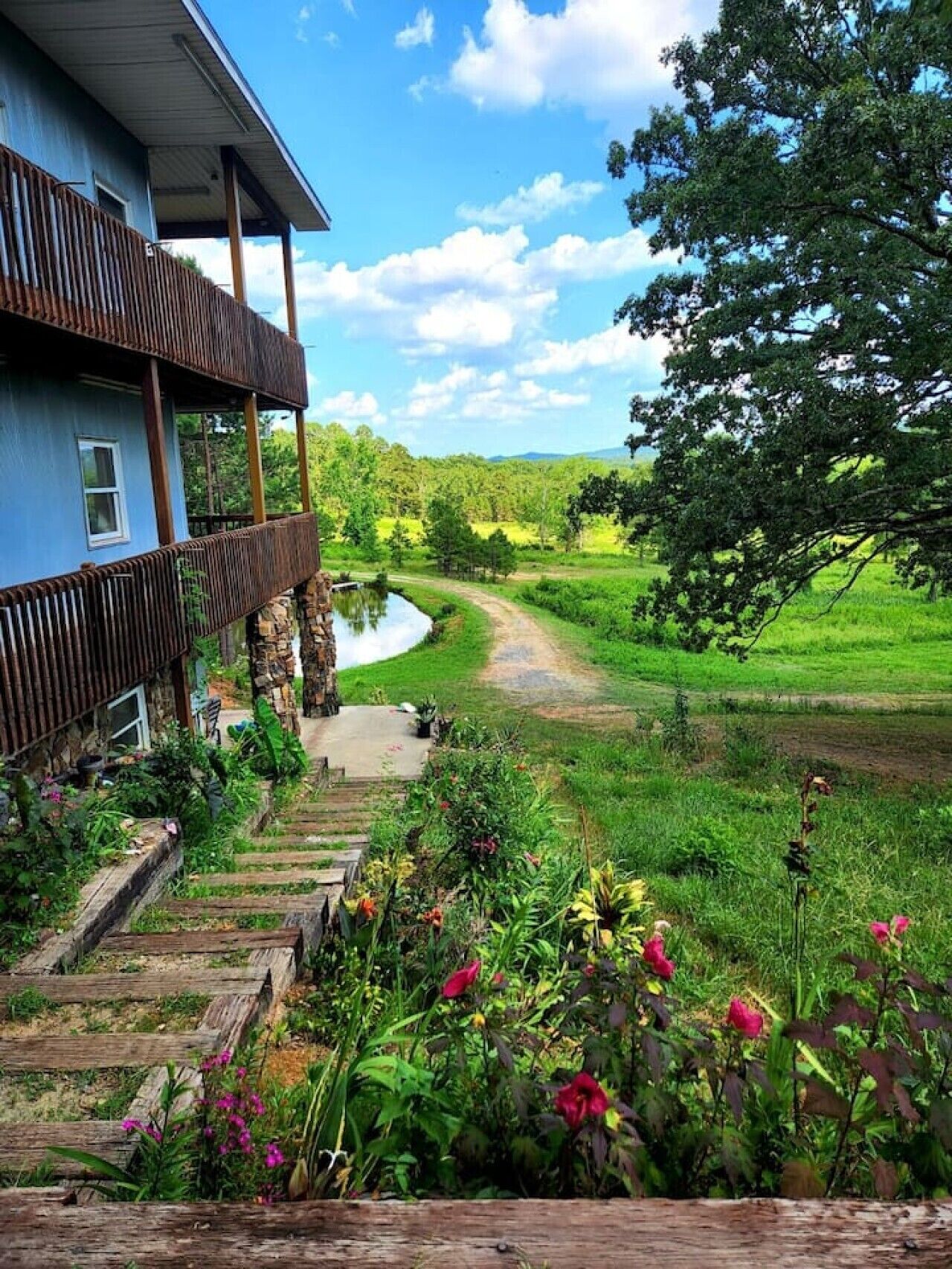Een huis met een houten terras en een tuin die uitkomt bij een rivier.