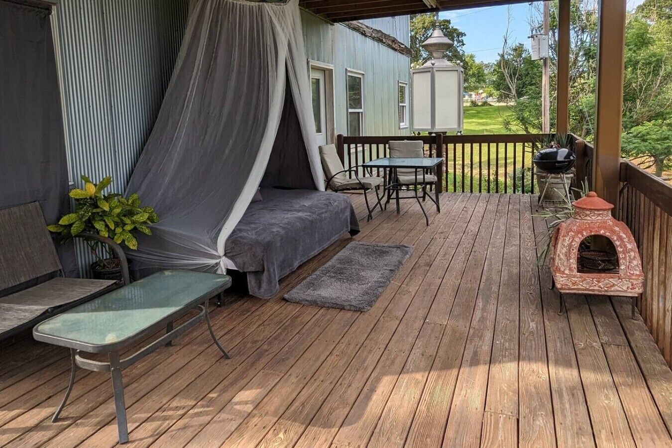 Une terrasse en bois dotée d’un espace salon couvert, d’une table et d’un petit four d’extérieur.