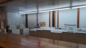 A laundry room with multiple washing machines and dryers, wooden cabinets, and a wooden counter. - Glamping Deck Amazing View! (Oden)