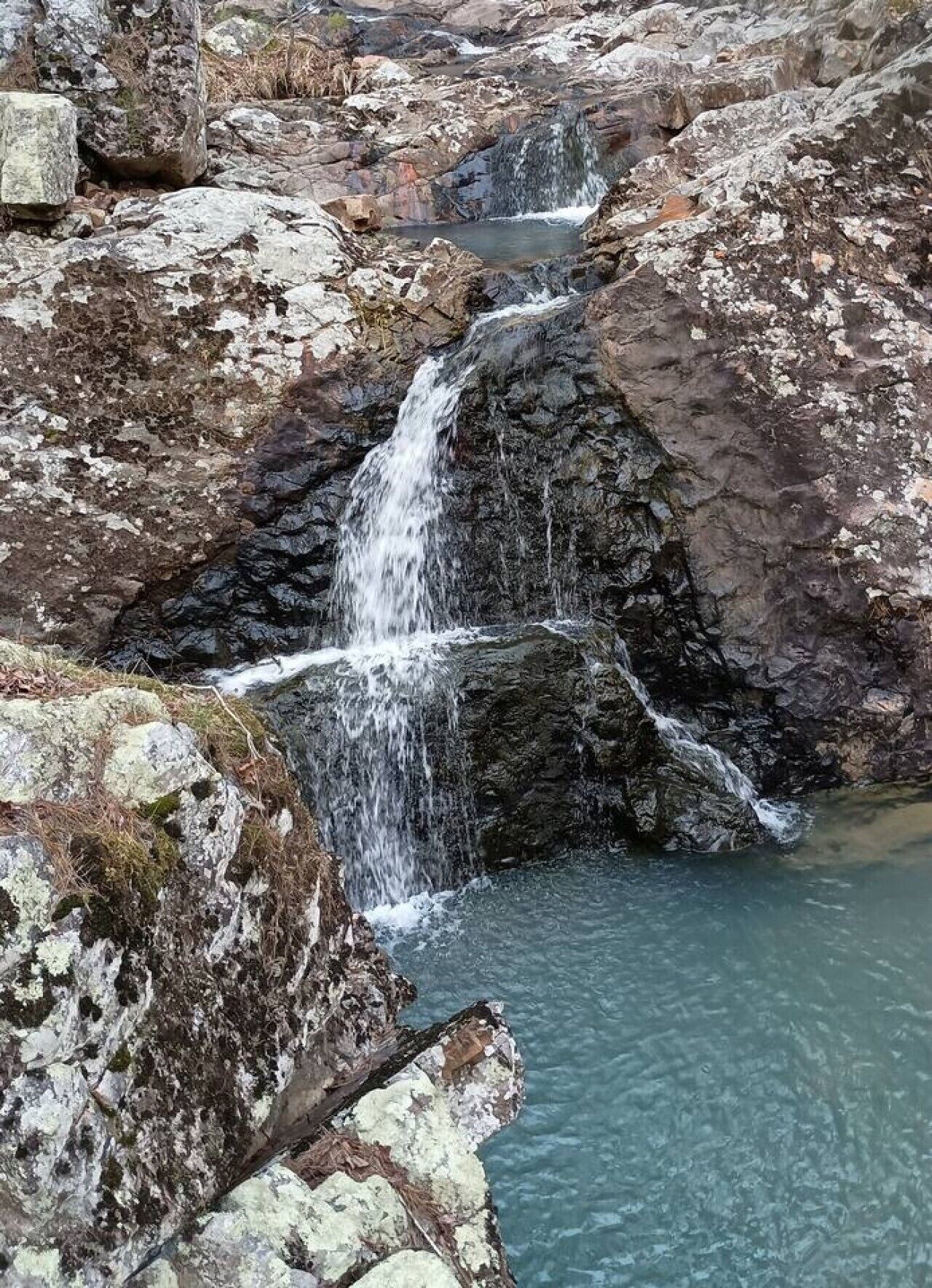Formación rocosa natural con una cascada y una poza en la base.