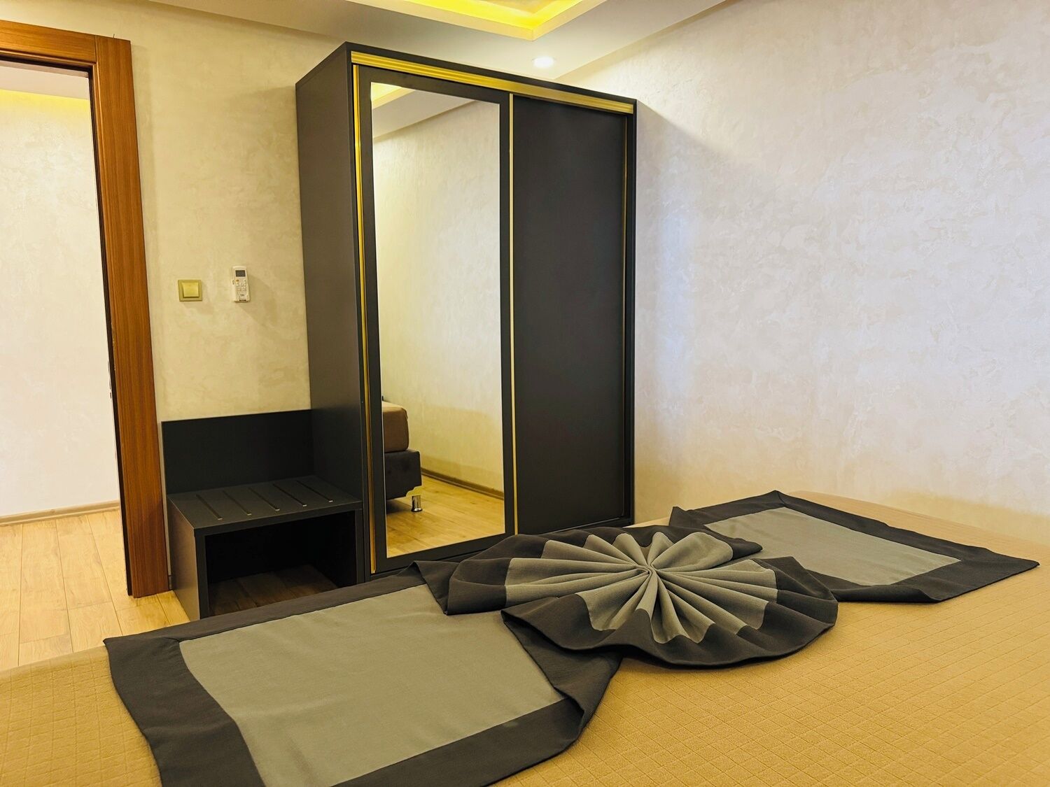 Ein modernes Hotelzimmer mit einem großen Spiegel, einer kleinen Sitzecke und einem Bett mit einem außergewöhnlichen Zierkopf.