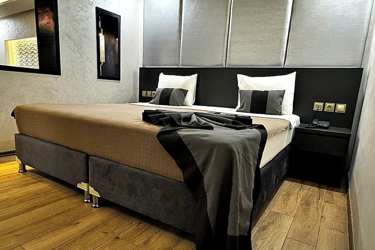 A modern bedroom with a large bed, a nightstand, and a wall-mounted light fixture.