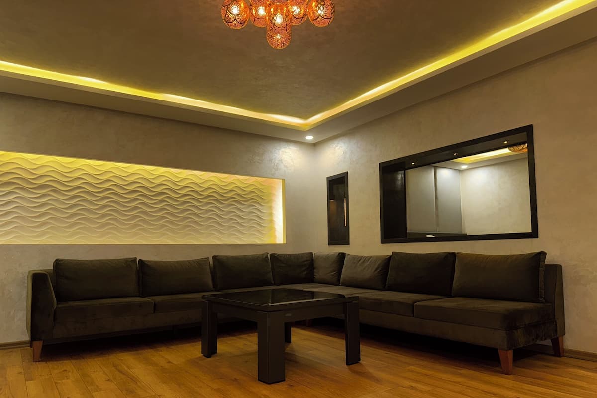 A modern living room with a sectional sofa, a coffee table, and a decorative wall panel.