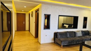 Una habitación de hotel moderna con piso de madera, un sofá gris y un espejo grande en la pared.