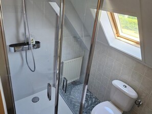 Une salle de bain moderne avec une douche, des toilettes et une petite fenêtre.