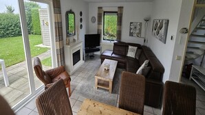 Un salon comprenant un canapé, des fauteuils, une table basse, un téléviseur et une cheminée.