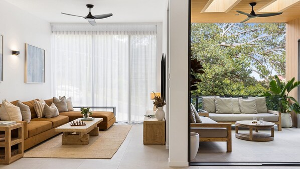A modern living room with a sofa, coffee table, and a view of the outdoors.