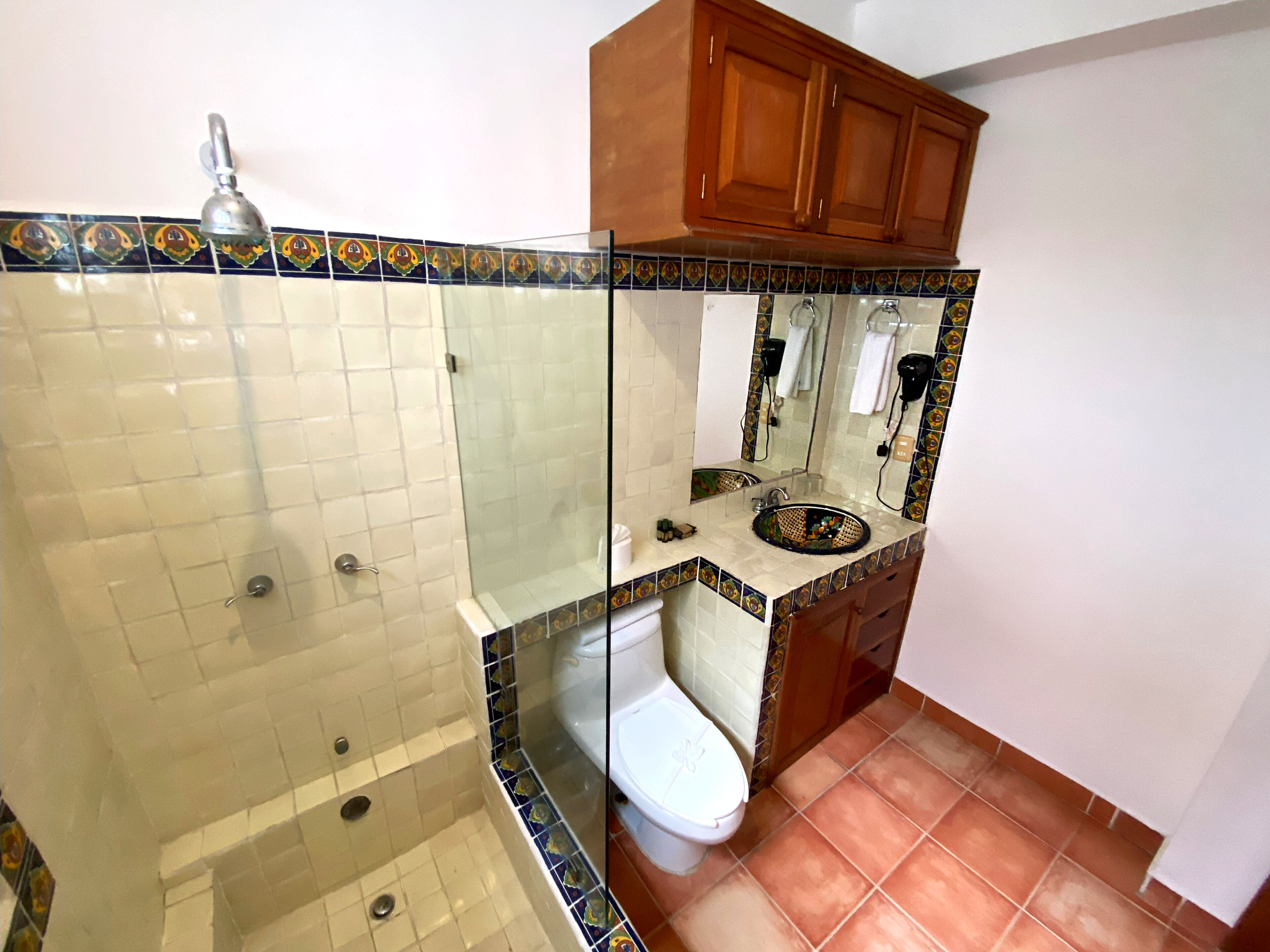 Un baño con ducha de vidrio, inodoro blanco y lavamanos con un elegante revestimiento de azulejos.