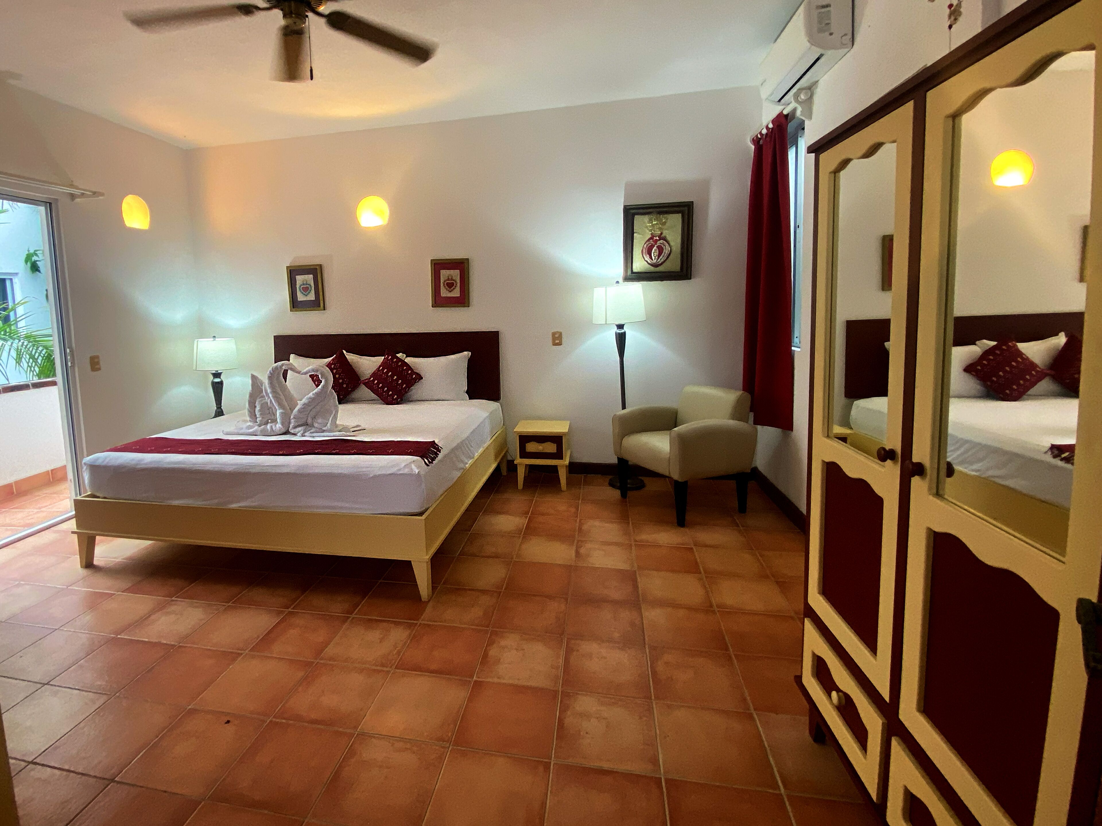 A hotel room with a bed, a chair, a nightstand, a lamp, and a wardrobe.