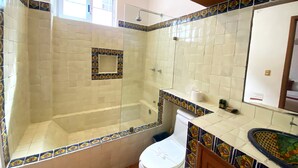 Uma casa de banho com chuveiro, sanita e janela.