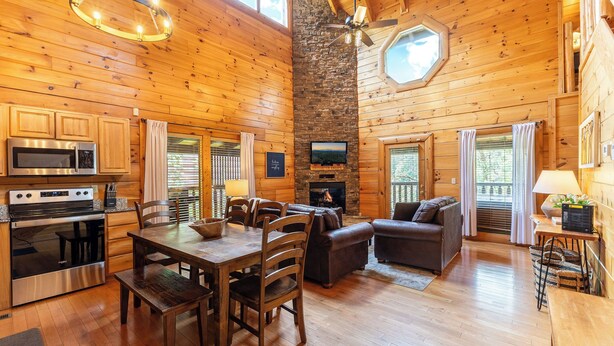 A spacious wooden cabin with a dining area, kitchen, and living room. - Smoky Traditions-Luxury Cabin,Gated,Pools,Mini-golf, Brand New Multi-Game Arcade (Sevierville)