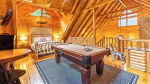 A wooden interior with a pool table, a bed, and a staircase. - Smoky Traditions-Luxury Cabin,Gated,Pools,Mini-golf, Brand New Multi-Game Arcade (Sevierville)