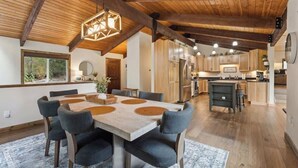 Un'ampia cucina con travi in legno, un'area pranzo con un tavolo e sedie capienti, e vista sull'esterno da una finestra.