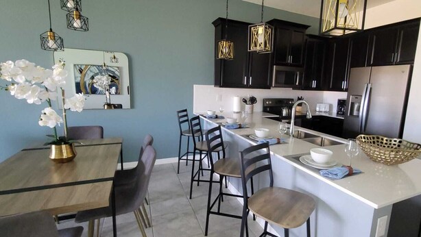 Una cocina moderna con armarios negros, electrodomésticos de acero inoxidable y una isla central con asientos.