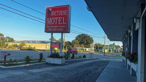 Schild eines Motels mit Palmenlogo, der Aufschrift 'Nocturne Motel' und einer Telefonnummer.