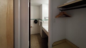 Ein schmaler Flur mit einer zur Toilette führenden Tür. Ein Handtuchhalter und eine kleine Ablagefläche mit einigen Gegenständen sind vorhanden.