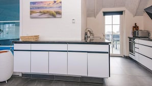 Una cocina moderna con una isla grande, armarios blancos y vistas al exterior.