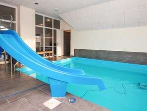 An indoor swimming pool with a blue slide, a bench, and a tiled floor. - 4 Star Holiday Home in Ulfborg (Ulfborg)