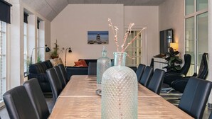 Un salón de conferencias con una larga mesa, sillas negras y jarrones decorativos.
