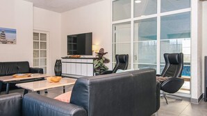 Una sala de estar moderna con un sofá, sillas, un televisor y una chimenea.