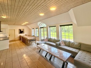 Une pièce spacieuse avec une longue table à manger, un canapé et un banc.