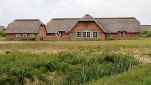 A row of brick buildings with thatched roofs, a central door, and windows. - 4 Star Holiday Home in Ulfborg (Ulfborg)