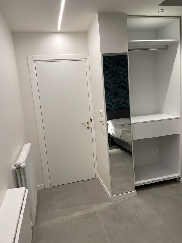 A bedroom with a white door, a bed with a white mattress, and a wardrobe with a mirrored door. - Ognina Sea (Catania)