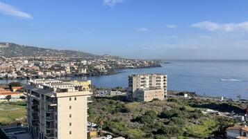 Un paisaje urbano costero con edificios modernos, un puerto deportivo y vistas al mar.