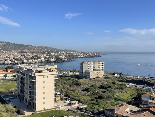 A coastal cityscape with modern buildings, a marina, and a view of the sea.
